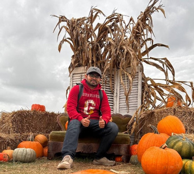 Abrar Faiyaz posing with pumpkins and smiling at camera